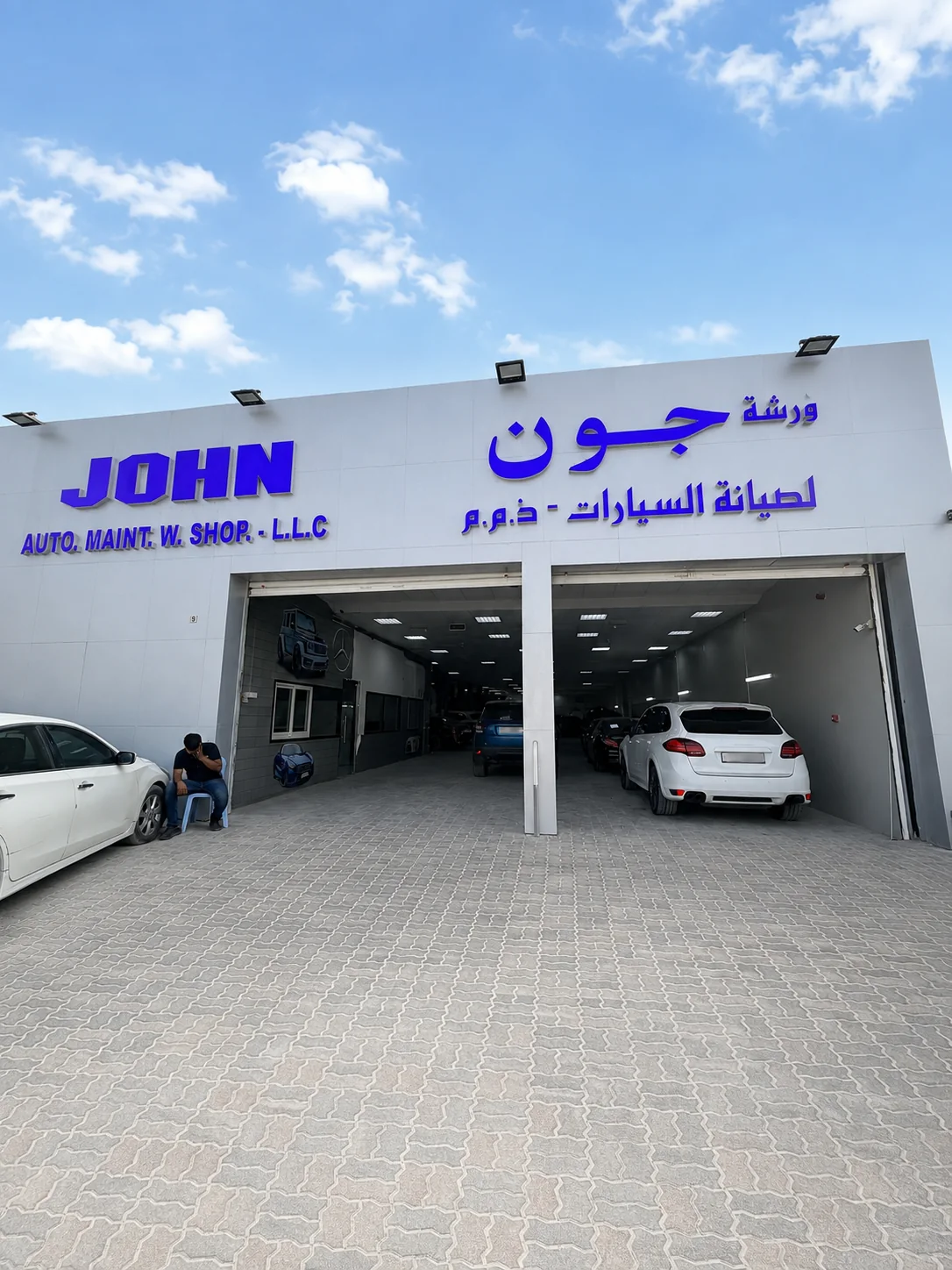 Front entrance and illuminated signage of John Auto Maintenance Workshop in Sharjah